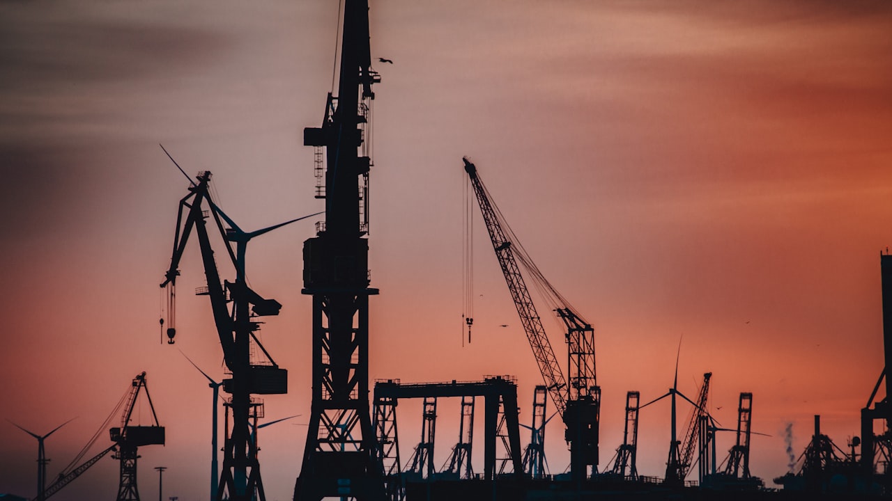 Ship-to-shore gantry cranes silhouetted at sunset