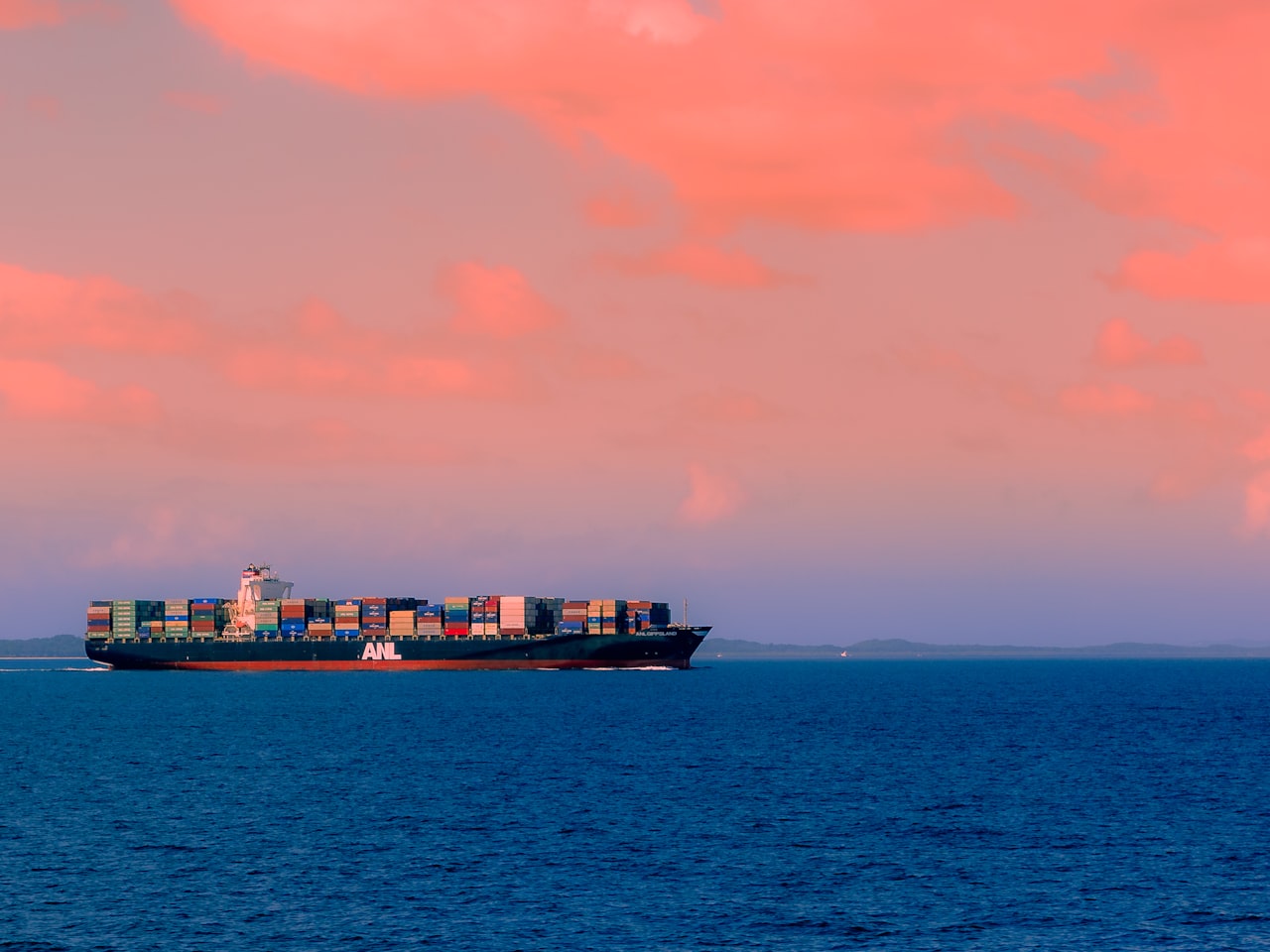 A container ship under way on open sea beneath heavy cloud